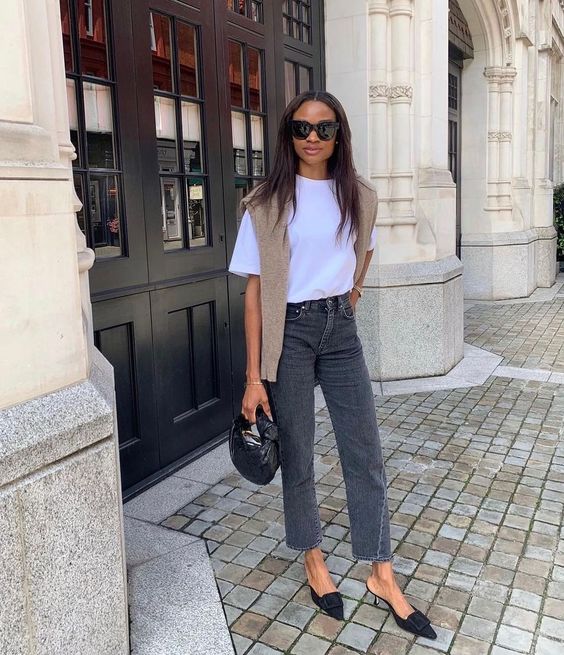 a white tee, grey jeans, black kitten heels, a beige jumper over the shoulders, a small black bag are a simple and elegant look for spring