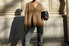 grey straight leg jeans, black minimalist shoes, a beige cardigan as a top, a black clutch are a chic and feminine outfit