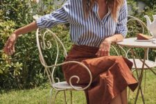 a blue striped shirt, a rust-colored linen midi skirt, brown shoes for a Parisian style look in spring
