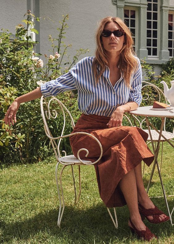 a blue striped shirt, a rust-colored linen midi skirt, brown shoes for a Parisian style look in spring