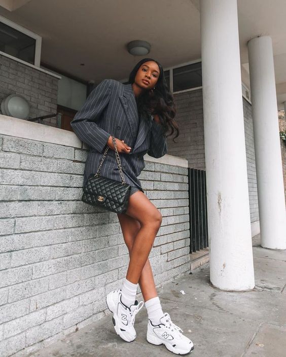 a grey thin stripe suit with a mini skirt and a blazer, white trainers and socks, a black bag with chain for an elegant look