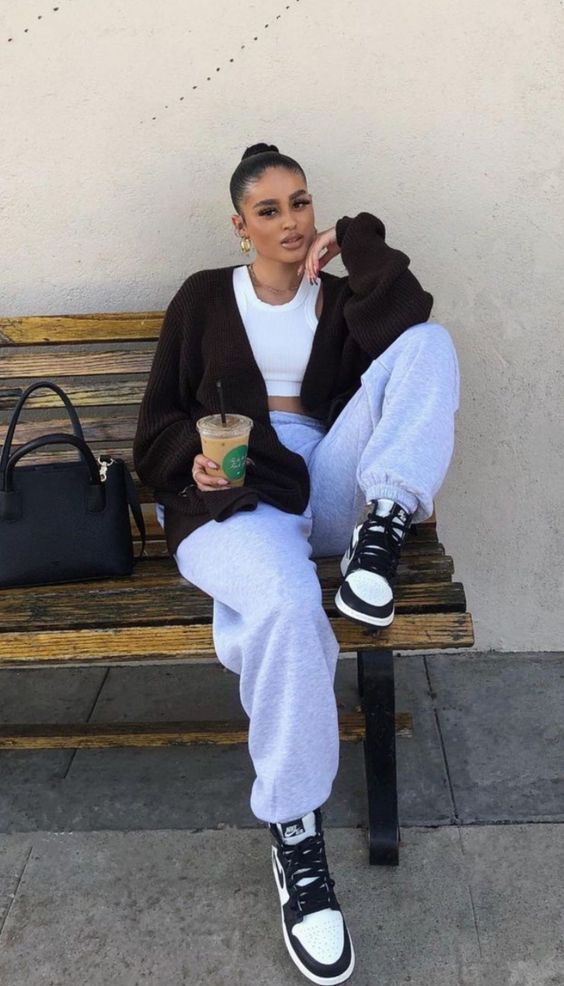 a white crop top, grey sweatpants, a black cardigan, black and white Jordan trainers and a black bag