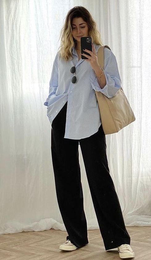 a blue striped shirt, black trousers, neutral sneakers and a tan tote are a gerat and comfy look for spring