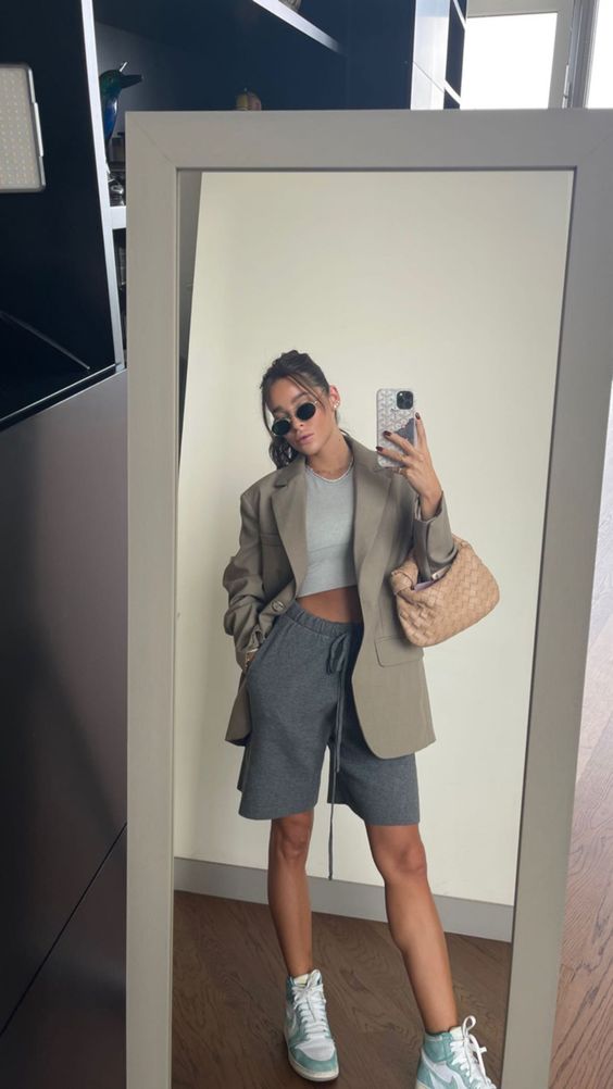 a sport chic look with a grey crop top, graphite grey shorts, a greige blazer, green Jordan sneakers and a woven bag