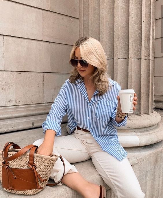 a blue striped shirt, neutral pants, a straw bag and sunglasses are a timeless look for spring and summer