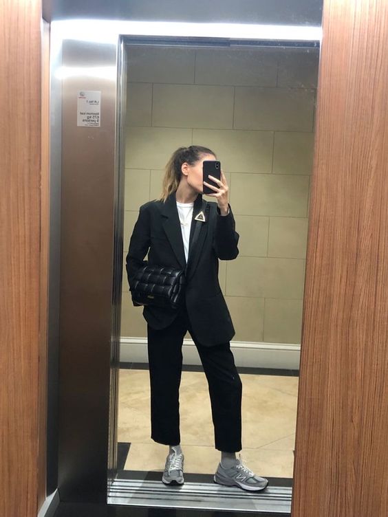 a black pantsuit, a white t-shirt, grey New Balance trainers and socks, a black woven bag for spring