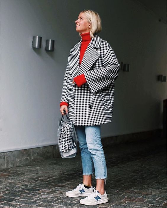 a bold look with a red sweater, cropped blue jeans, an oversized printed coat, white sneakers and a catchy bag