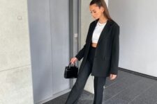 22 a black pantsuit, a white crop top, black and white Jordan trainers and a small black bag compose an elegant outfit