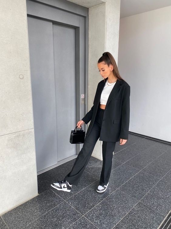 a black pantsuit, a white crop top, black and white Jordan trainers and a small black bag compose an elegant outfit