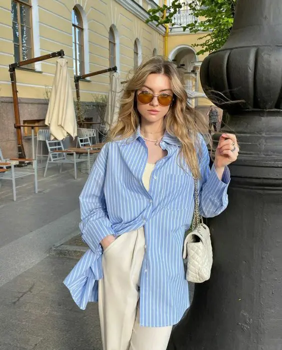 a neutral top and trousers, a blue striped shirt, a creamy bag are a great look for spring or even summer