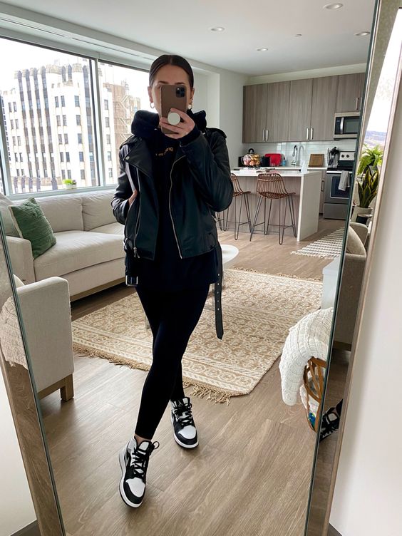 a cool monochromatic outfit with a black hoodie, leggings, a leather jacket, Jordan sneakers is great for spring or dall
