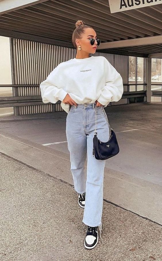 a creamy sweatshirt, bleached blue jeans, black and white Jordan trainers, a black mini bag and statement earrings are cool for spring