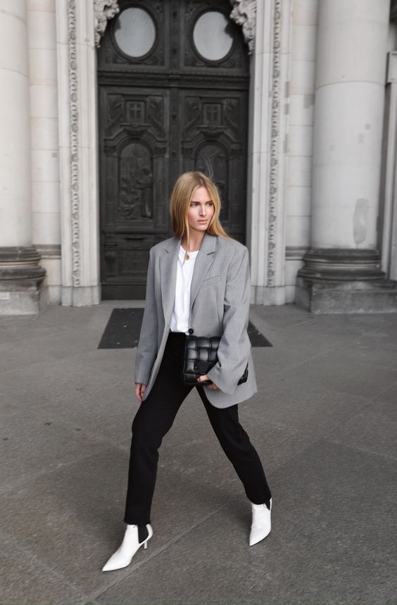 a white t-shirt, black jeans, a grey oversized blazer, white Chelsea boots with heels and a black woven bag for spring