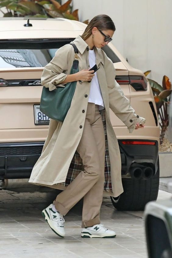 a simple spring look with a white t-shirt, beige trousers, a tan trench, white New Balance trainers, a green hobo bag