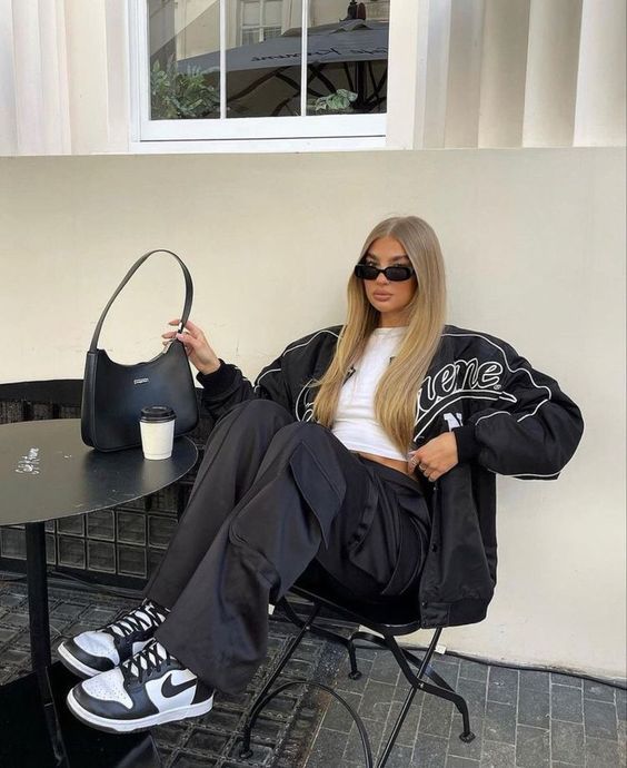 a white crop top, black cargo pants, a black bomber jacket, a black mini bag for a spirty and comfy look