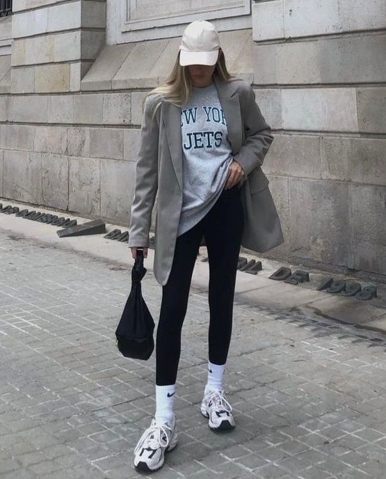an athleisure look with a grey oversized t-shirt, black leggings, white trainers and socks, a black bag and a grey oversized blazer