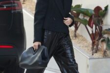 35 black leather trousers, black and white Jordan sneakers, a large black clutch and sunglasses are an edgy look