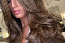 a beautiful long brunette butterfly haircut with curtain bangs and a bit of golden blonde balayage is amazing