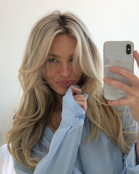 a bleached blonde butterfly haircut on long hair, with a darker root, wavy ends and a bit of volume is a stylish up-to-date idea