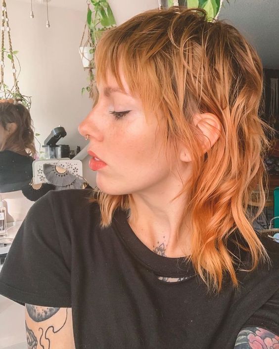 a catchy ginger mullet with shaggy touches, with bangs, shorter hair on top and longer hair on the back and sides