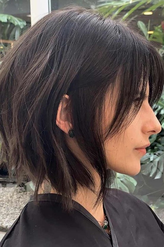 a choppy dark brunette bob with bangs and slight waves is a bold and chic idea