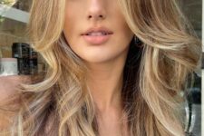 a fab bronde butterfly haircut with blonde highlights and face-framing locks, with wavy ends and a lot of volume