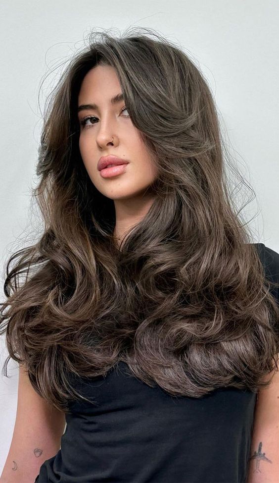 a fab dark brunette long butterfly haircut with long curtain bangs and curled ends and a lot of volume is jaw-dropping