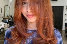 a long and beautiful ginger butterfly haircut with curled ends and bottleneck bangs is a cool and bold idea