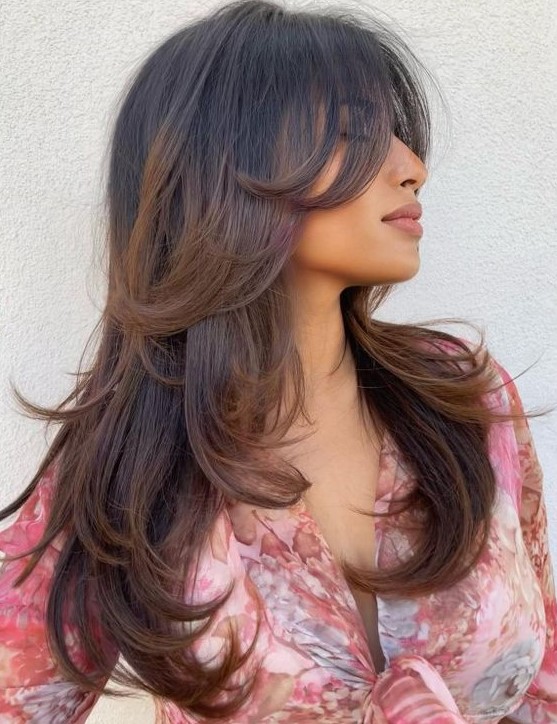 a long black butterfly haircut with brown balayage and bottleneck bangs plus curled ends is a bold and chic idea