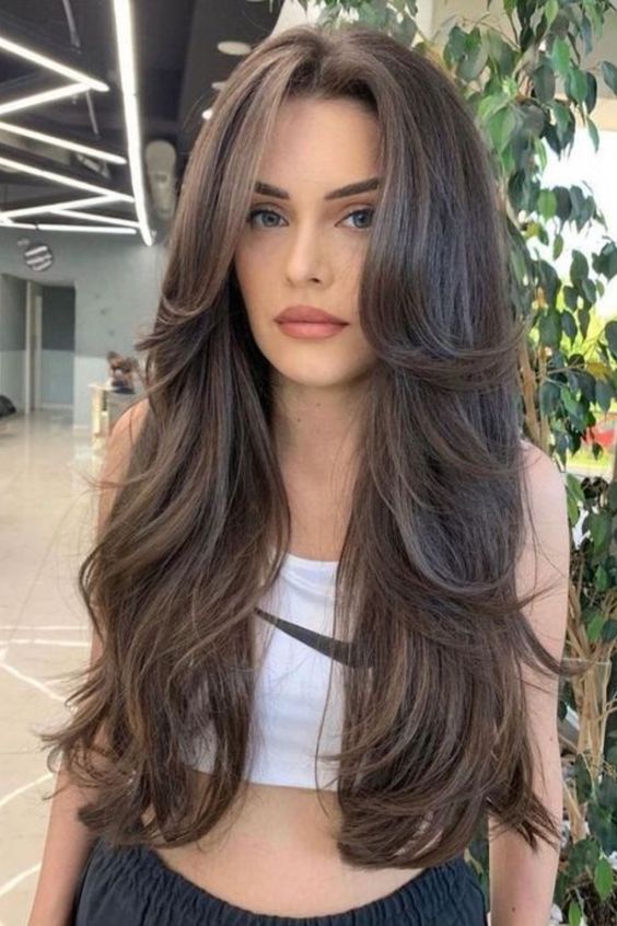 a long brunette butterfly haircut with curled ends and a lot of volume is amazing to torck
