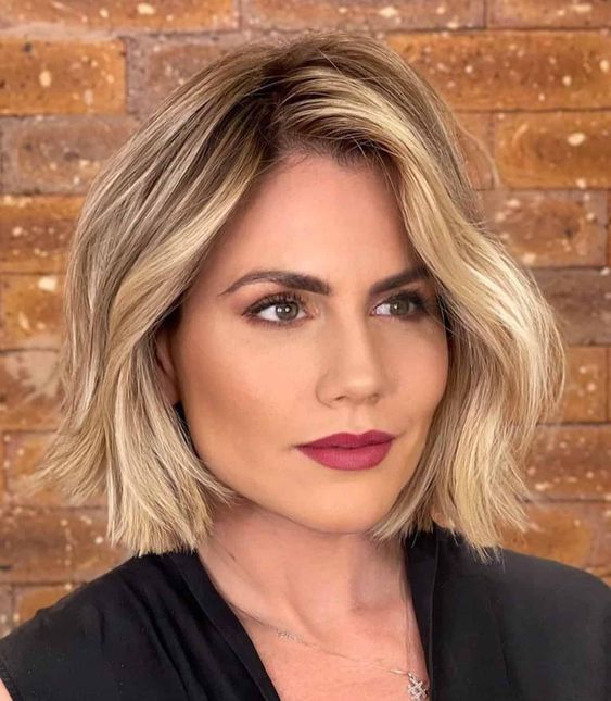 a pretty and a bit wavy blonde chin length bob with a darker root is a lovely and holiday-like idea