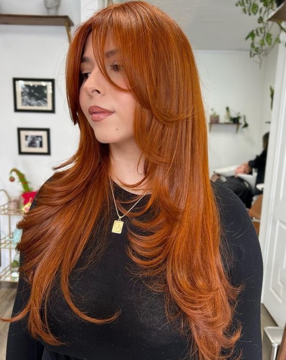 A stunning bright copper long butterfly haircut with face framing layers and curled ends is amazing