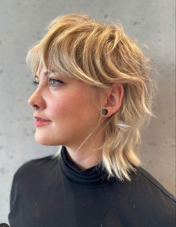a textural mullet n blonde shades, with bangs, longer hair on top and shorter hair on the sides and back