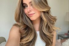 chic mushroom brown long hair with a butterfly haircut, with waves that highlight the layers and some caramel highlights