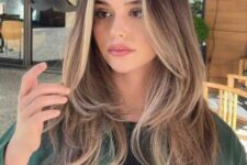 long bronde hair with blonde money piece, centra part and a butterfly haircut with feathered layers for a dimensional look