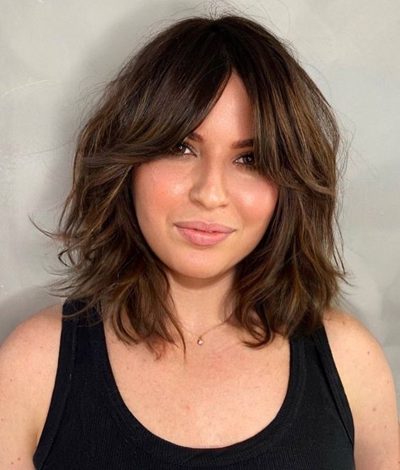 medium length chestnut hair with short curtains bangs and messy waves is a chic and beautiful idea with a romantic feel