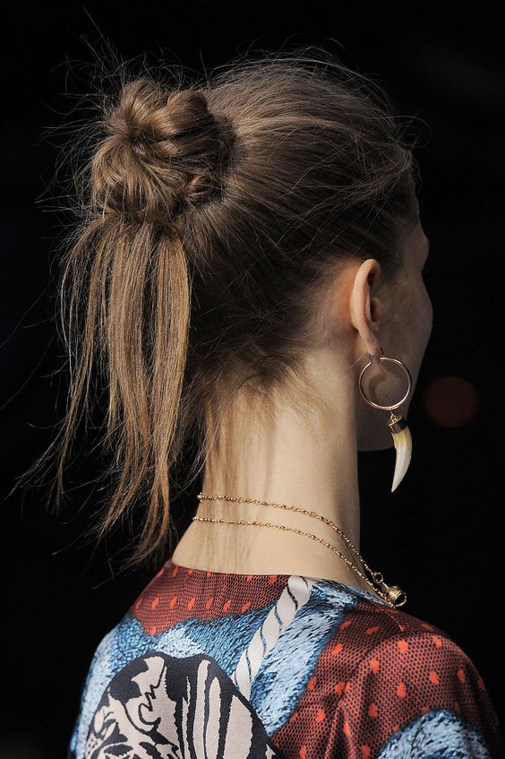 a messy and textured top knot with some hair hanging down and a messy top is a cool idea with a boho feel