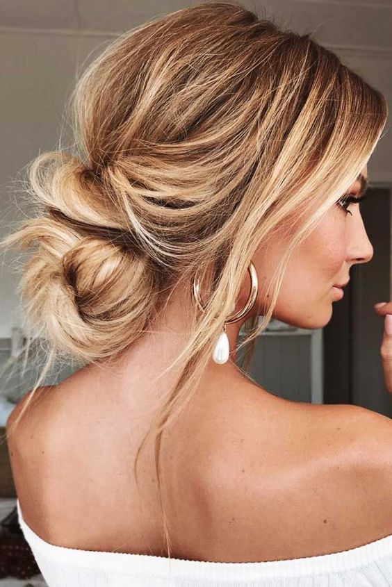 a messy low bun on long hair, with a bump and some locks down is a cool and chic idea