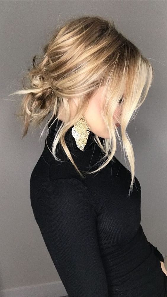 a low messy updo on medium hair, with some textured hair and some locks down that frame the face