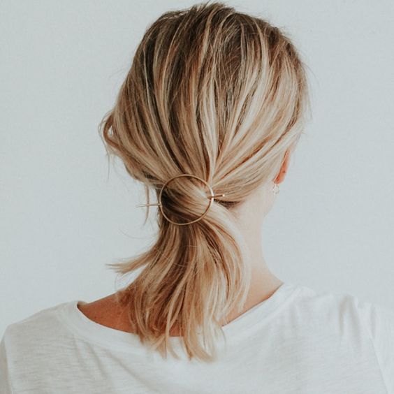 a fast and simple twisted low ponytail with a messy top and a modern hair accessory that secures it
