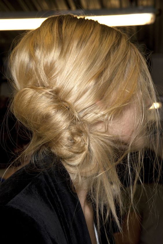 a very messy low French twist hairstyle with a bump on top and some textured locks down is a cool idea