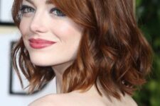 Emma Stone wearing a ginger red long bob with side part and waves looks gorgeous and very bold