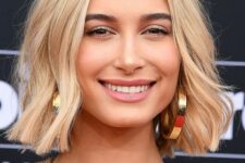 Hailey Bieber wearing a gold blonde long bob with waves, central parting and a lot of texture looks really posh