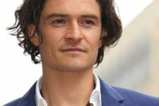 Orlando Bloom wearing a dark brown wavy and curly bob with layers looks stylish and very romantic