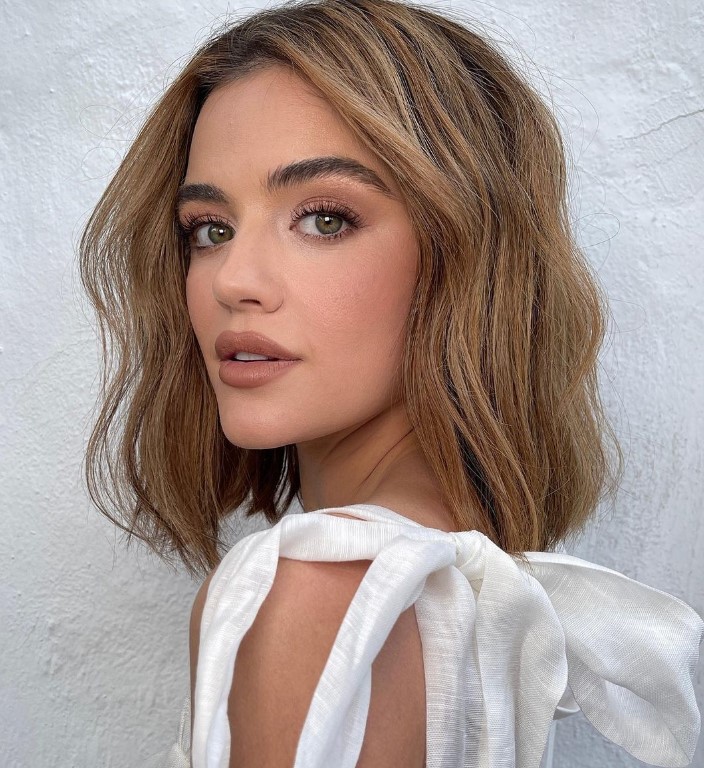 a beautiful middle-part outgrown bob that just about sweeps her shoulders, with caramel balayage and a bit of waves
