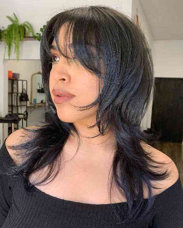 a black medium-length octopus haircut with wispy bangs will keep the length but take out weight if your hair is too thick