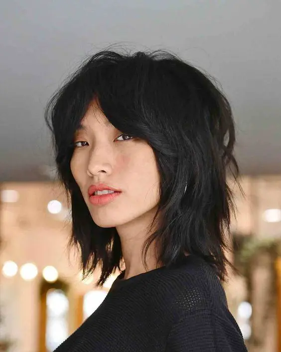 a black wolf cut with bottleneck bangs and layers, with central part is a catchy idea, and styled with messy waves it looks edgier
