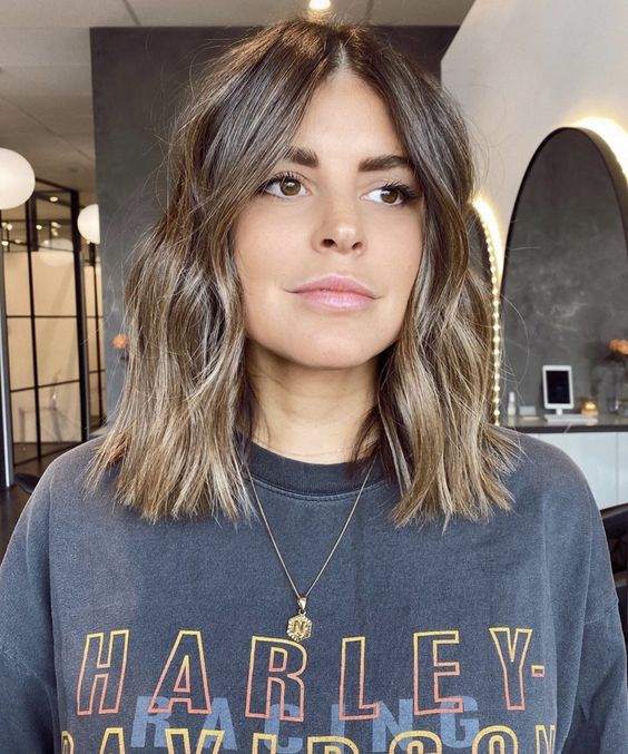 a brown outgrown bob with blonde balayage, with waves and central part is a chic and cool idea for trying now