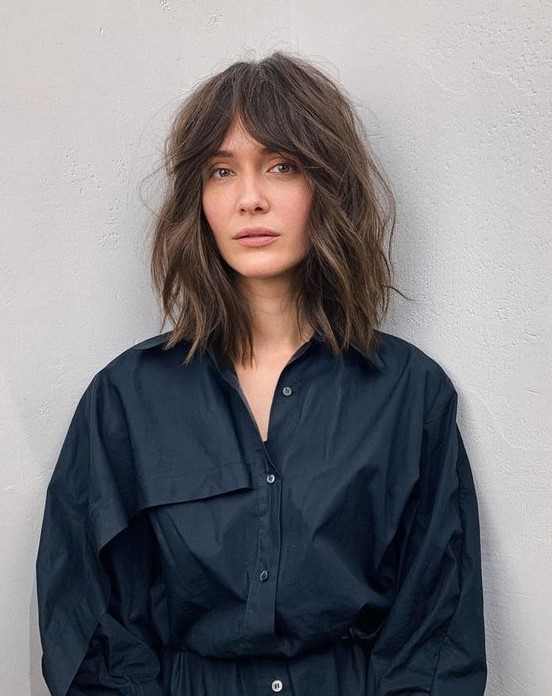 a brown outgrown bob with slight highlights, messy waves and bottleneck bangs is a trendy solution to rock now