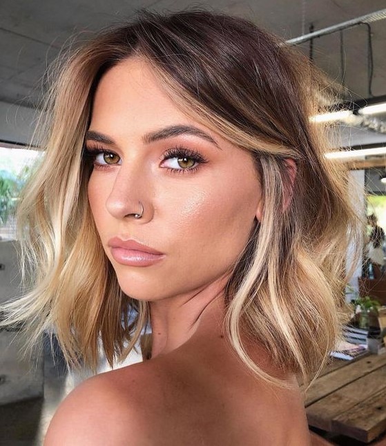 a brunette wavy shoulder-length bob with honey blonde balayage and a money piece is cool